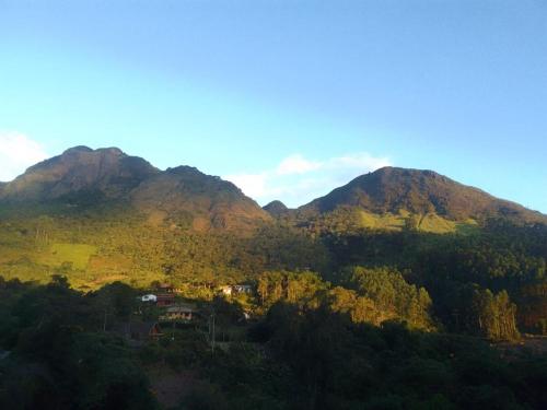 a view of a mountain with trees and a house at Refúgio encanto das montanhas in Nova Friburgo