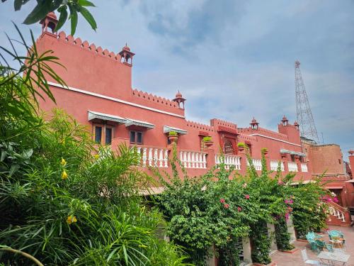 a large red building with plants in front of it at Cavalry Villa bikaner in Bikaner