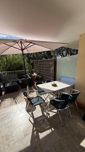 Una mesa y sillas con una sombrilla en un patio. en Modern apartment with sunny terrace, en Niza