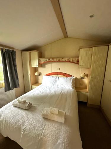 a bedroom with a white bed with two towels on it at Relaxing static stay Holiday park in Northampton