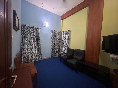 a living room with a couch and a flat screen tv at Anugraha inn in Guruvāyūr