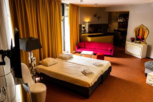 a bedroom with a bed and a pink couch at Hotel De Elderschans in Aardenburg