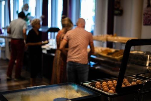 a group of people standing around a buffet line with food at Hotel De Elderschans in Aardenburg