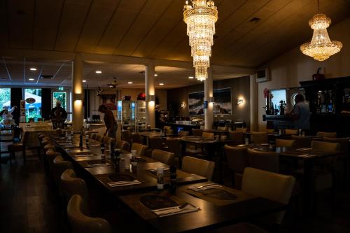 a dining room with tables and chairs and chandeliers at Hotel De Elderschans in Aardenburg