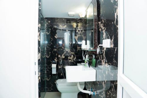 a black and white bathroom with a sink and a toilet at Nilo's Guest House in Batticaloa