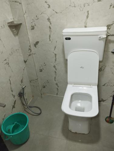 a bathroom with a white toilet and a bucket at Sunlight Dormitory in Mumbai