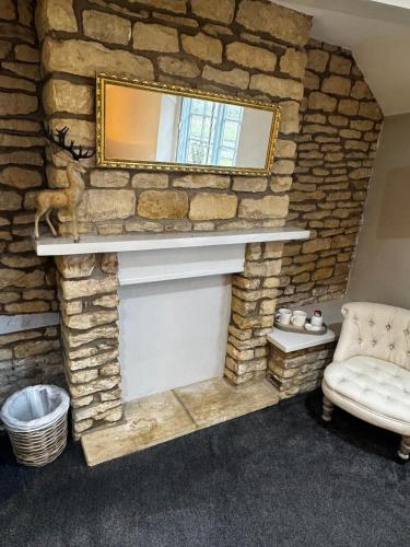 a stone fireplace with a mirror and a chair at The Royal Oak Duddington in Stamford
