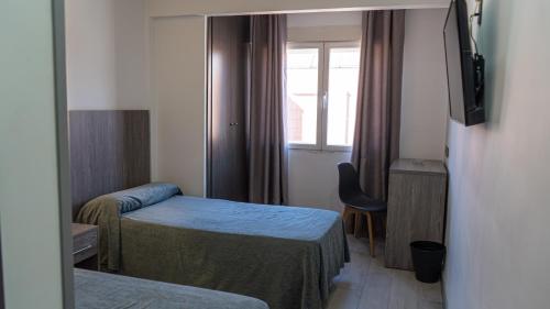a small room with two beds and a window at Hostal Goyma III in San Fernando de Henares