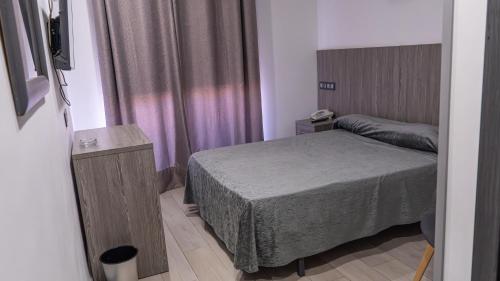 a small bedroom with a bed and a television at Hostal Goyma III in San Fernando de Henares
