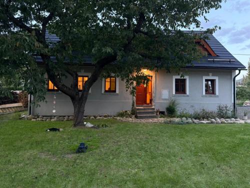 a small white house with a tree in the yard at Chalupa mezi stezkami in Hejnice