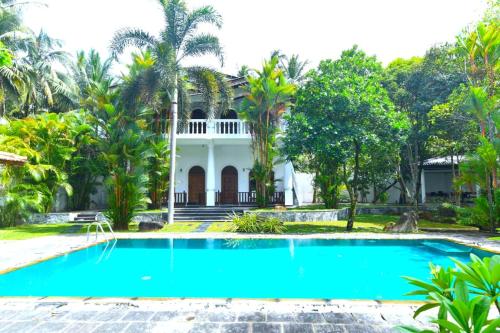 a villa with a swimming pool in front of a house at oZean Villa in Talpe
