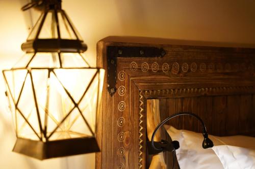 a lamp on a bed next to a wooden headboard at Eden Boutique Hotel in Tamellalt