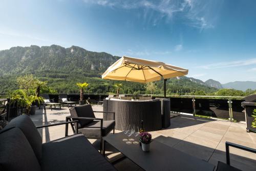 a patio with tables and an umbrella and mountains at Ferienhaus Goldener Anker Unterach am Attersee in Unterach am Attersee