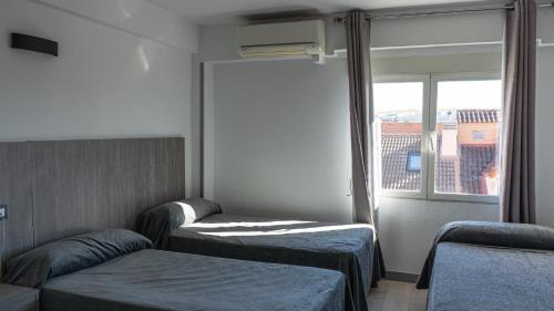 a room with two beds and a window at Hostal Goyma III in San Fernando de Henares