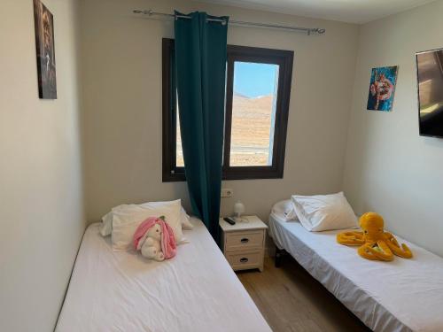 two twin beds in a room with a window at Corralejo Branded Residensed in Corralejo