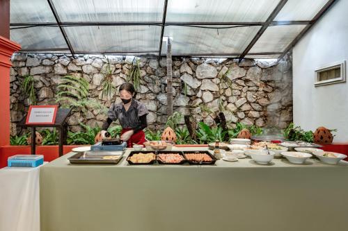 una donna che prepara il cibo su un tavolo con un buffet di Manyo Hotel and Resort a Luang Prabang