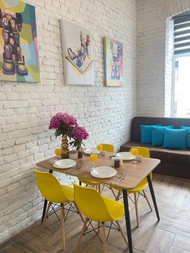 a dining room with a wooden table and yellow chairs at Квартира-студія в історичному центрі міста біля Центральної площі in Chernivtsi
