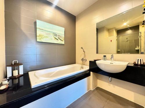 a bathroom with a tub and a sink and a bath tub at Veloche Peaceful Condo In Karon Beach in Ban Karon
