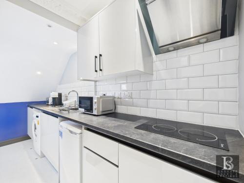a kitchen with white cabinets and a counter top at Luxury room's with ensuite and kitchen, parking in Slough Centre in Slough