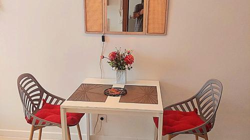 昂蒂布Ravissant studio au coeur du Vieil Antibes的一张桌子,两把椅子,花瓶上放着鲜花