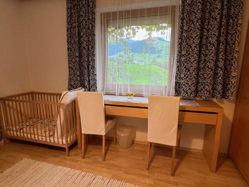 a desk with two chairs in front of a window at Ferienwohnung Christ in Grinzens