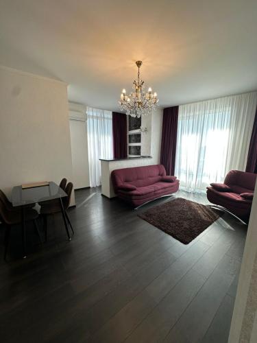 sala de estar con sofá rojo y lámpara de araña en Panorama Dnipro apartment, en Dobrovelychkivka