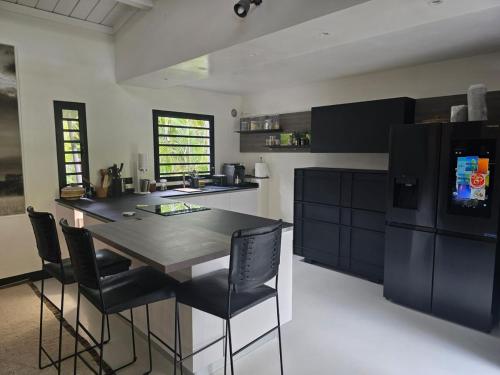 a kitchen with a black table and chairs in it at L'Eden, villa d'exception entre océan & forêt in Saint-Paul