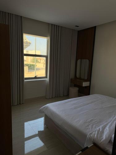 a bedroom with a white bed and a window at شقة غرفة وصالة اطلالة على البرج in Al Kharj