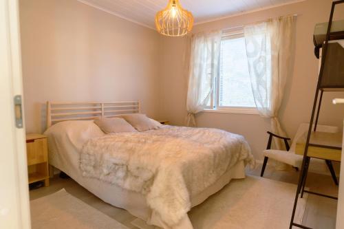 een slaapkamer met een bed, een raam en een kroonluchter bij Villa Valaja in Rovaniemi