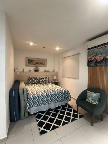 a bedroom with a bed and a chair at Loft Porto Marina Itacuruçá in Mangaratiba