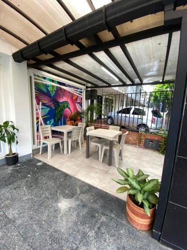 een patio met tafels en stoelen en een schilderij aan de muur bij Hotel pasarela real cali in Cali
