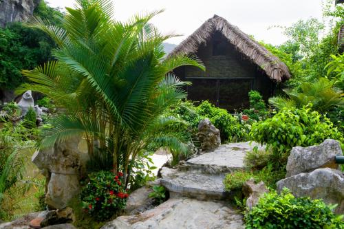 a palm tree in front of a house at Tam Coc Lion Kings Hotel & Resort Ninh Binh in Ninh Binh