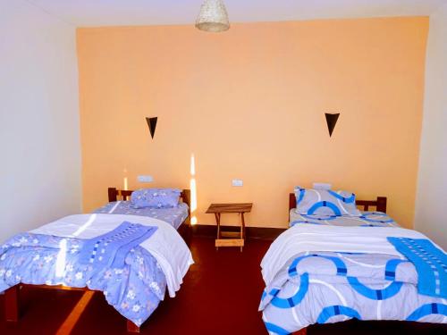 ムトワンブにあるAnapa Lodge and Campの青と白のシーツが敷かれた部屋にベッドが2つある