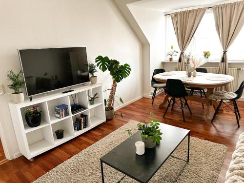 a living room with a television and a table with chairs at Deluxe Apartment on the Main Street with Free Parking & Late Checkout in Herning