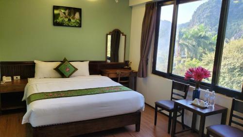 a bedroom with a bed and a desk and a window at Tam Coc Lion Kings Hotel & Resort Ninh Binh in Ninh Binh