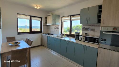 una cocina con armarios azules y una mesa. en Casa Bot, en Predeluţ