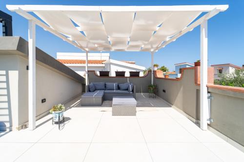 a patio with a white pergola on a roof at Villa Tea con piscina a pochi passi dal mare in Fontane Bianche