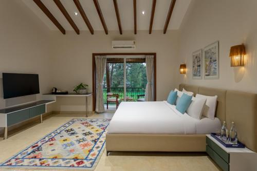 a bedroom with a large bed and a television at Lamrin Morjim Goa in Morjim
