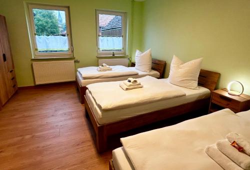 a hotel room with two beds and two windows at FEWO Unterm Stein - Hänsel & Gretel - 2 Schlafzimmer in Alheim