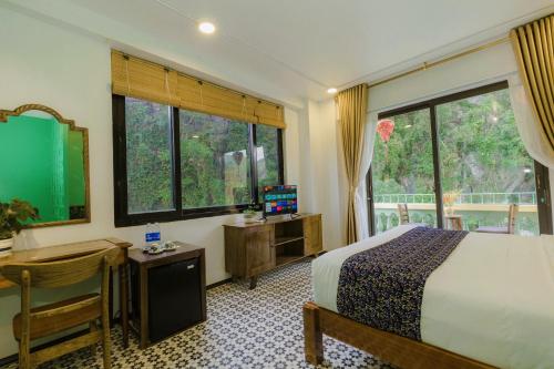 a bedroom with a bed and a desk and windows at Tam Coc Lion Kings Hotel & Resort Ninh Binh in Ninh Binh