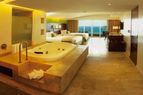 a hotel room with a bath tub and a bedroom at Azul Ixtapa Grand All Inclusive Suites - Spa & Convention Center in Ixtapa