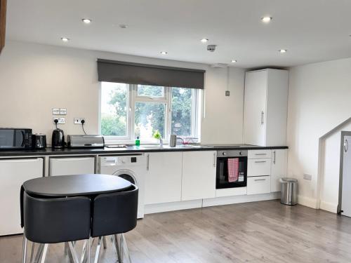 a kitchen with white cabinets and a table and chairs at Hatton apartments HEATHROW AIRPORT- FREE parking-Free underground to and from Heathrow Airport Hatton Cross SEE picture-SEE LONDON fast Hatton cross to central London 30min in London