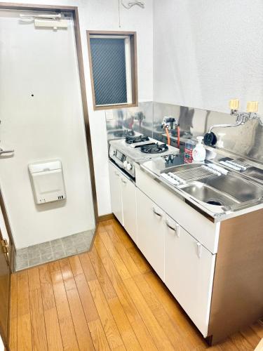 a kitchen with a stove and a sink at 折尾Inホテル305 in Kitakyushu
