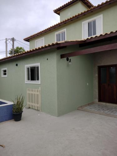 une maison verte avec une allée en face de celle-ci dans l'établissement Casa em Buzios, à Búzios