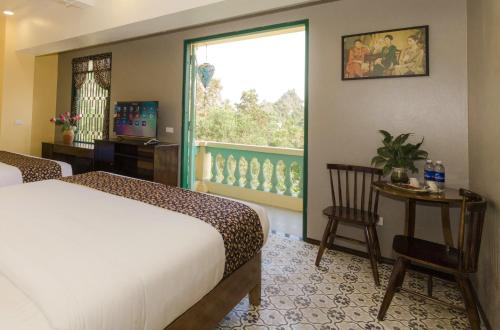 a bedroom with a bed and a window and a table at Tam Coc Lion Kings Hotel & Resort Ninh Binh in Ninh Binh