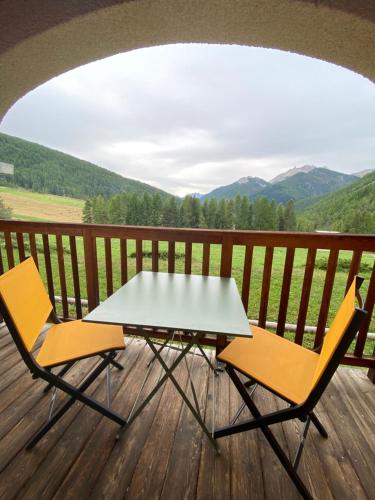 a table and two chairs on a deck with a view at Granges d'Arvieux, Splendide T2, Rdc, Vue dégagée in Arvieux