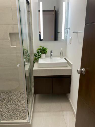 a bathroom with a sink and a shower with a mirror at Depto Moderno Oceanna frente a playa cerritos in Mazatlán