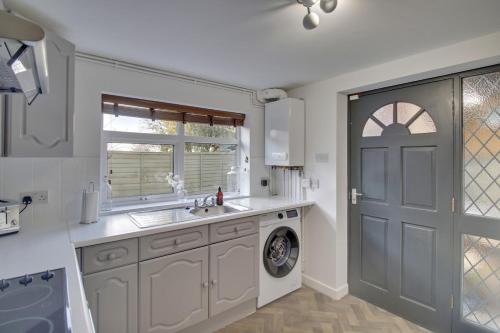 a kitchen with a sink and a washing machine at Stylish spacious apartment near airport, Rawdon in Rawdon
