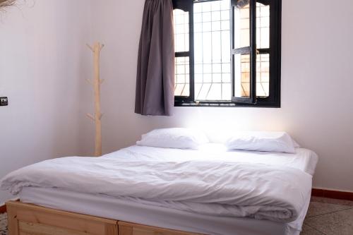a bedroom with a white bed with two windows at Azurf - Imsouane Surf House in Imsouane