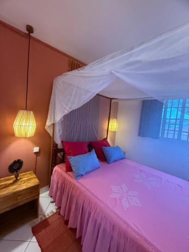 a bedroom with a pink bed with a canopy at Appartement Chez Tourab in Nosy Be